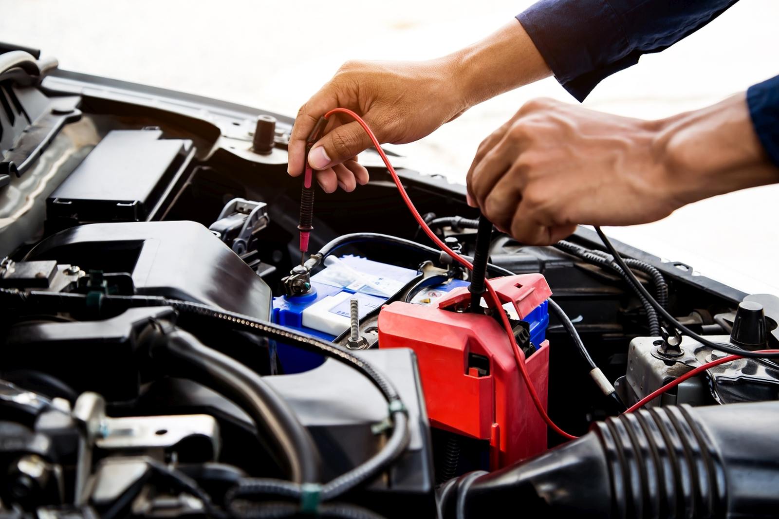 Auto mechanic using measuring equipment for checking car battery. Concepts of car Repair service and car insurance.